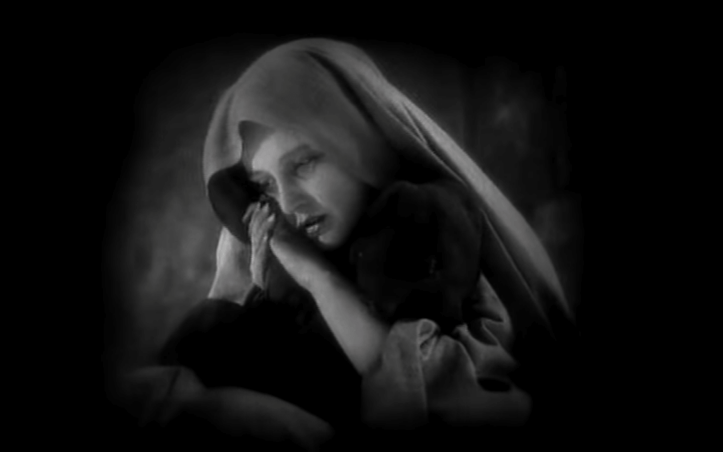 Still from Faust (1926): The outcast Gretchen is warming her dying child like a Madonna figure in the winter storm.